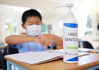 Image showing Boy rubbing hand sanitizer for hygiene, safety and protection against covid at school. Closeup bottle of alcohol gel on desk in classroom to clean, kill or prevent the spread of germs or coronavirus