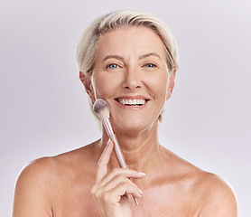 Image showing Beauty, skincare and makeup with a senior woman applying cosmetics to her face in studio against a purple background. Head portrait of a female with blusher looking beautiful, happy and healthy