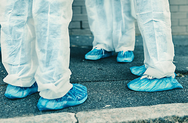 Image showing Legs and feet of healthcare workers wearing protective gear or hazmat suits outdoors while cleaning. Closeup of a team of medical professionals meeting during the covid or coronavirus pandemic