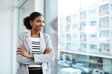 Image showing Young professional businesswoman, smiling while looking out of window of her modern office, thinking in her leadership role. Happy female manager standing with the vision of ambitious motivation