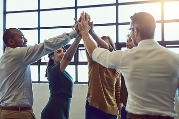 Image showing Team of cheerful colleagues celebrate with high five after hearing good news at the office. Diverse team winning and supporting each other. Professional and successful people standing together.