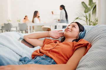Image showing Relaxing, carefree and listening to music with a young business woman thinking, resting and lying in an office during break. Enjoying the comfort of a beanbag chair and working as a creative designer