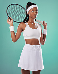 Image showing Trendy tennis player, fit athlete and active woman ready to play with racket in cool sports uniform while posing against a green studio background. Competitive, determined and serious young female