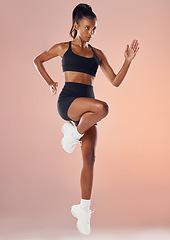 Image showing Active, healthy, sport and fitness athlete is determined and focused on her running exercise workout. Young woman with fit body, wearing gym sportswear, doing cardio training in studio background