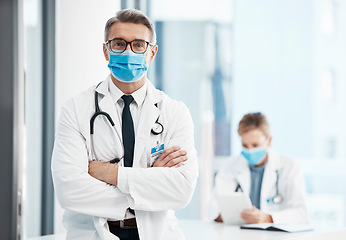 Image showing Doctor, physician or healthcare professional with covid face mask in a hospital for medical health insurance background. Innovation, leadership and excellence male gp portrait with his arms crossed