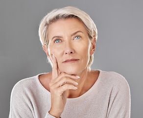 Image showing Mature, thinking and woman touching her face in isolated grey studio background. Copy space for anti ageing skincare or cosmetic products for senior feeling her skin and wrinkles headshot.