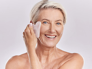 Image showing Skin care, hygiene and grooming by mature woman using a gua sha stone while giving herself a face massage. Happy senior female dace enjoying a beauty skincare routine to refresh and smooth wrinkles