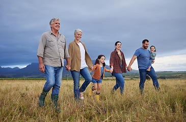 Image showing Big happy family walking on field, meadow and countryside in nature to relax, bond and holding hands in love, trust and support. Generation of grandparents, parents and kids having fun outside