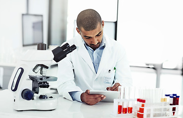 Image showing Scientist writing DNA results from microscope test on a tablet.Professional male doctor in a lab working with research tubes.Man in a modern laboratory doing medical science data analysis.