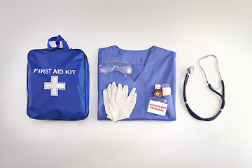 Image showing Medical kit, doctor scrubs and hospital equipment on a table for safety and healthcare in a clinic from above. Flat and top view of a bag, uniform and stethoscope on a desk before a procedure