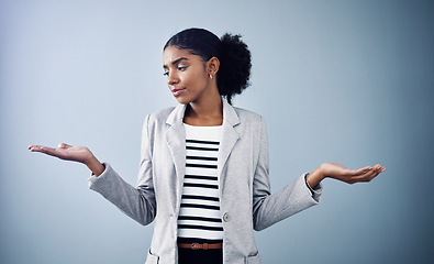 Image showing Decisions, choices and options with a young business woman comparing and weighing up different decisions with copyspace in studio against a grey background. Picking between two balanced ideas