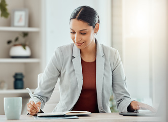 Image showing Female manager, boss or CEO writing notes in her diary, marking appointments in her calendar or organizing a schedule. Corporate professional feeling motivated and working at her desk in the office