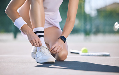 Image showing Female tennis player foot and hands tying shoelaces before game match on outdoor sports court. Active, sporty woman preparing for training for fun, summer exercise and healthy, wellness lifestyle.