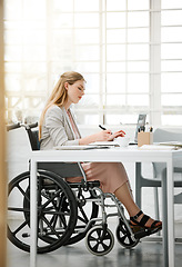 Image showing Professional, disabled business woman in wheelchair reading documents, writing or making notes on office desk sitting by laptop. Female entrepreneur with disability doing contract paperwork with pen.