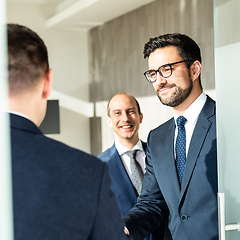 Image showing Group of confident business people greeting with a handshake at business meeting in modern office or closing the deal agreement by shaking hands.