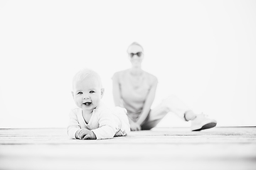 Image showing Happy family. Young mother playing with her baby boy infant oudoors on sunny autumn day. Portrait of mom and little son on wooden platform by lake. Positive human emotions, feelings, joy.