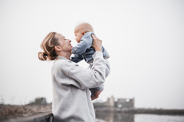 Image showing Tender woman caressing her little baby boy infant child outdoors on autumn trip to Secovlje salinas landscape park, Slovenia. Mother's unconditional love for her child.