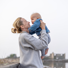 Image showing Tender woman caressing her little baby boy infant child outdoors on autumn trip to Secovlje salinas landscape park, Slovenia. Mother's unconditional love for her child.