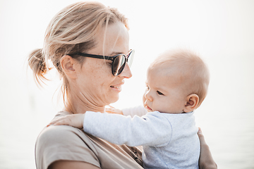 Image showing Tender woman caressing her little baby boy infant child outdoors. Mother's unconditional love for her child