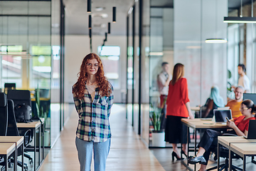 Image showing A portrait of a young businesswoman with modern orange hair captures her poised presence in a hallway of a contemporary startup coworking center, embodying individuality and professional confidence.