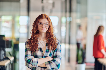 Image showing A portrait of a young businesswoman with modern orange hair captures her poised presence in a hallway of a contemporary startup coworking center, embodying individuality and professional confidence.