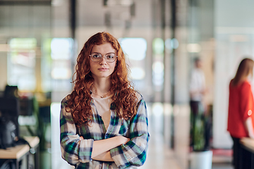 Image showing A portrait of a young businesswoman with modern orange hair captures her poised presence in a hallway of a contemporary startup coworking center, embodying individuality and professional confidence.