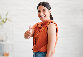 Image showing Positive young woman treated with covid vaccine injection, gestures thumbs up and showing her arm to approve immunization. Happy healthy female patient wearing bandaid after her treatment shot