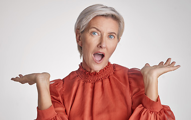 Image showing Mature surprised, wow and shocked woman face against a grey copy space grey studio background posing with her hands up and feeling unsure. Portrait of senior model making facial expression or emotion