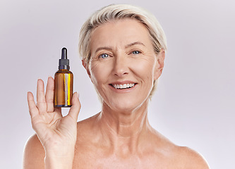 Image showing Skincare, beauty or makeup product in the hand of a senior woman holding face serum or cosmetic oil in studio on a purple background. Portrait of a female marketing, advertising or endorsing wellness