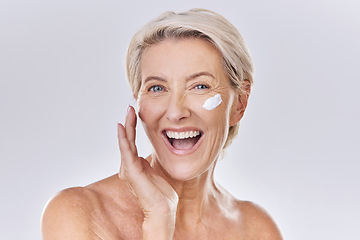 Image showing Beauty, skincare and wellness with a senior woman applying lotion, sunscreen or serum to her face in studio on a grey background. Health, skin care and motivation with a beautiful and healthy model
