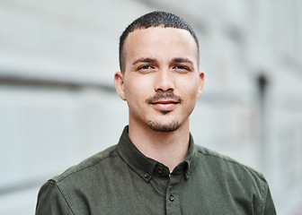 Image showing Closeup face of a serious, motivated and ambitious man standing outside in a city, town or downtown alone. Portrait, headshot and face of social worker or volunteer looking forward with trust or care
