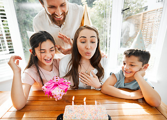 Image showing Birthday, family and celebration with a woman blowing the candles on her cake. Husband and kids spoiling mom and making her feel happy on her special day mothers day while having a party at home