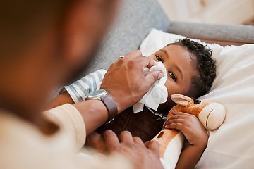 Image showing Sick, ill and unwell little boy suffering from cold, flu or covid and lying on the sofa at home while blowing his nose with dad. Cute son with a runny nose and resting in the living room from above