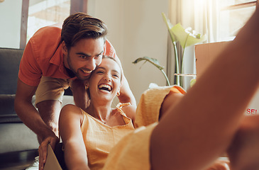 Image showing Fun couple moving into first house together, having fun and enjoying their freedom. Young newlyweds enjoying new home, fooling around and feeling excited. Cheerful homeowners playing while unpacking