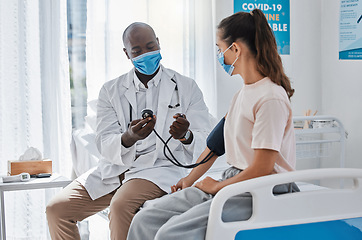 Image showing Doctor, blood pressure and healthcare medic checking womans hypertension levels on the hospital bed. People, healthy or sick patient doing medical test in covid 19 mask for pandemic safety protocol