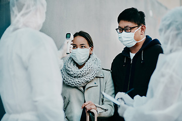 Image showing Traveling couple getting a covid temperature scan at the border with medical security doing screening test for safety during pandemic. Foreign people or traveler arriving at an airport with face mask