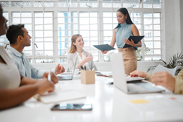 Image showing Female intern, assistant or employee handing out an information document to a team during a boardroom meeting. Group of business people discussing the mission, vision and strategy for company growth