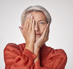 Image showing Beauty, health and wellness with a senior woman touching her face with her hands on a studio background. Headshot portrait of a person covering her eye with her hand to show good vision and skincare