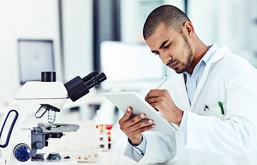 Image showing Serious male scientist working on a tablet reviewing an online phd publication in a lab. Laboratory worker updating health data for a science journal. Medical professional document clinical trial