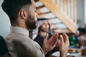 Image showing Muslim, praying and religion while sitting with family and say a dua or prayer before breaking fast during the holy month of Ramadan. Religious man lifting his hands to pray during eid or iftar meal