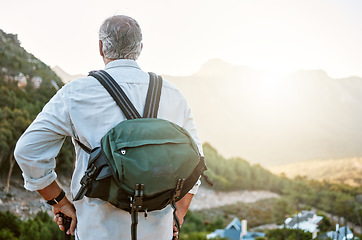 Image showing . Rear view of exploring, active and adventure senior man standing with a backpack after a hike, enjoying the landscape and forest nature. Male hiker looking at nature environment sunrise view.