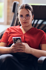 Image showing A businesswoman resting on a short break from work in a modern startup coworking center, using her smartphone to unwind and recharge.