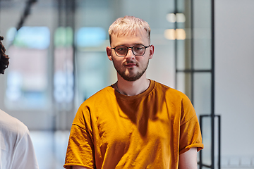 Image showing A modern portrait captures a blue-haired businessman wearing glasses, exuding creativity and professionalism, within the ambiance of a startup coworking office