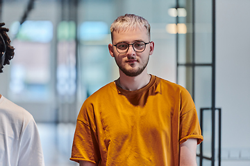 Image showing A modern portrait captures a blue-haired businessman wearing glasses, exuding creativity and professionalism, within the ambiance of a startup coworking office