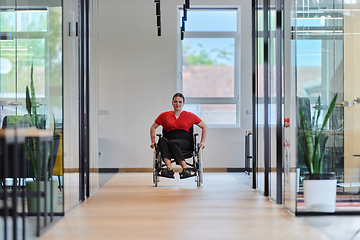 Image showing A modern young businesswoman in a wheelchair is surrounded by an inclusive workspace with glass-walled offices, embodying determination and innovation in the business world