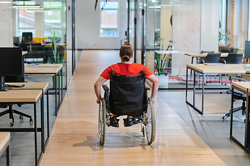 Image showing A modern young businesswoman in a wheelchair is surrounded by an inclusive workspace with glass-walled offices, embodying determination and innovation in the business world