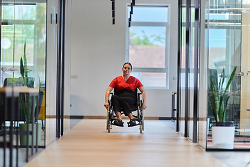 Image showing A modern young businesswoman in a wheelchair is surrounded by an inclusive workspace with glass-walled offices, embodying determination and innovation in the business world