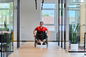 Image showing A modern young businesswoman in a wheelchair is surrounded by an inclusive workspace with glass-walled offices, embodying determination and innovation in the business world