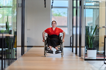 Image showing A modern young businesswoman in a wheelchair is surrounded by an inclusive workspace with glass-walled offices, embodying determination and innovation in the business world