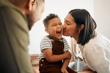 Image showing Happy boy getting a kiss by caring mother, bonding and laughing during family time at home. Young parents sharing a sweet moment of parenthood with their playful child, relaxing and carefree together